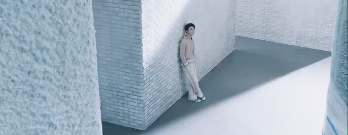 a man standing in a room with a brick wall