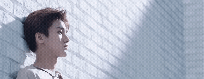 a man standing next to a brick wall