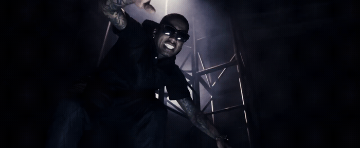 a man in sunglasses and a black shirt standing in a dark room