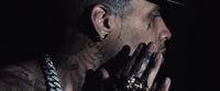 a man with tattoos holding his hands to his face