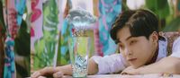 a young man leaning on a table with a glass of water in front of him