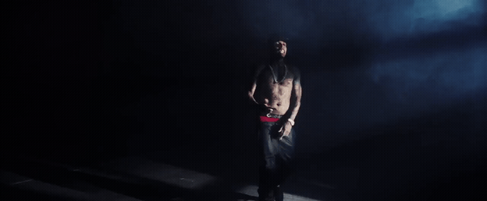 a shirtless man standing in a dark room