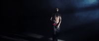 a shirtless man standing in a dark room