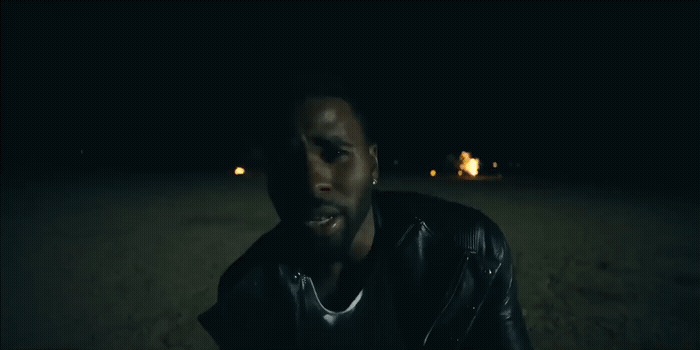 a man in a leather jacket sitting in the dark