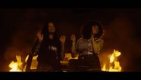 two women standing next to each other in front of a fire