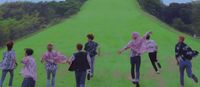 a group of people walking across a lush green field