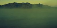 a foggy landscape with mountains in the distance