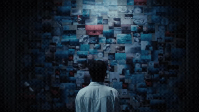 a man standing in front of a wall covered in pictures