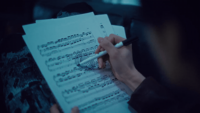 a person writing on a sheet of music