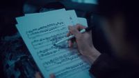 a person writing on a sheet of music