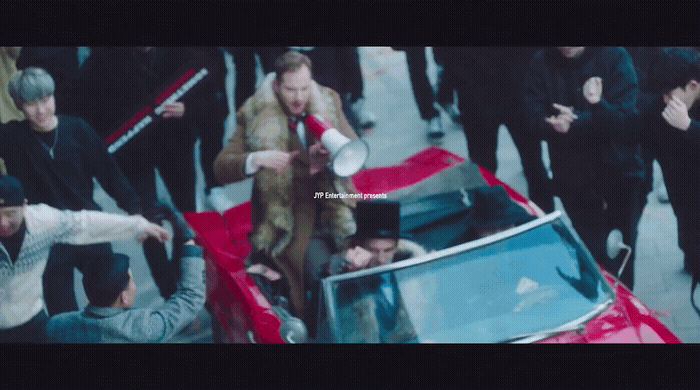a group of people standing around a red car