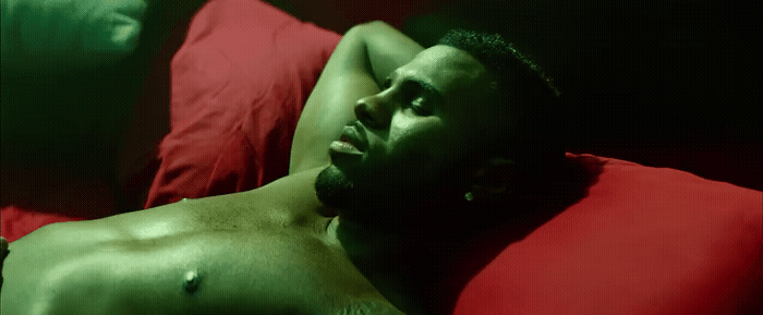a shirtless man laying on a red pillow