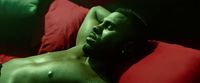 a shirtless man laying on a red pillow