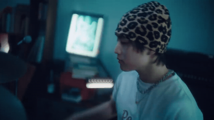 a young man wearing a leopard print hat in front of a computer