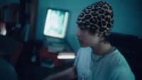 a young man wearing a leopard print hat in front of a computer