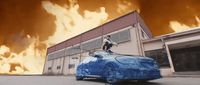 a blue car is parked in front of a building on fire
