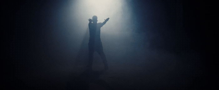 a person standing in the dark with their arms outstretched
