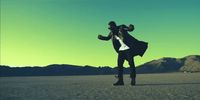 a man in a suit and hat is dancing in the desert