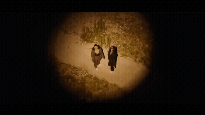 two women walking down a dirt road at night