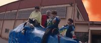 a group of young men riding on the back of a blue elephant