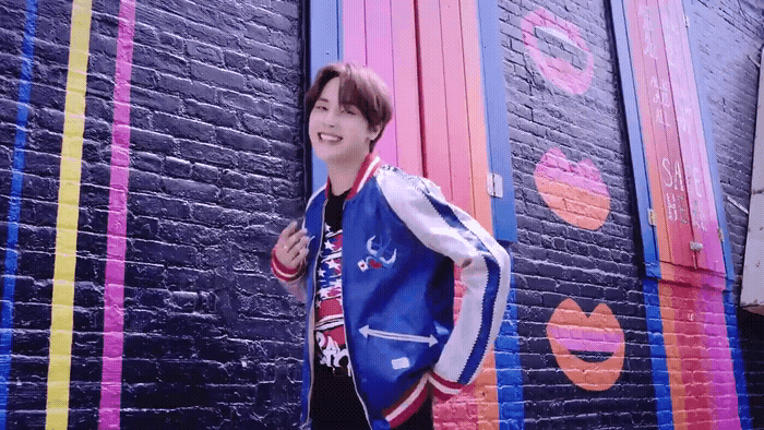 a young man standing in front of a colorful wall
