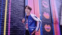 a young man standing in front of a colorful wall