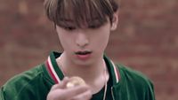 a boy in a green jacket holding a piece of food