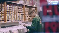 a woman standing in a store looking at a piece of paper