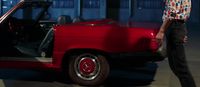 a man standing next to a red car
