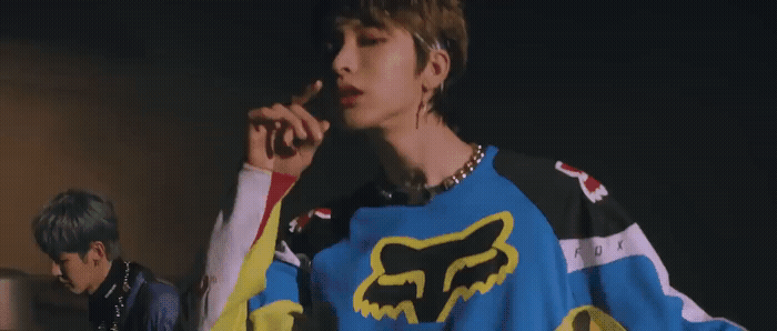 a young man smoking a cigarette while wearing a colorful sweater
