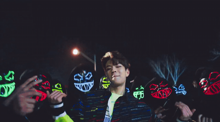 a man standing in front of a group of people wearing neon masks