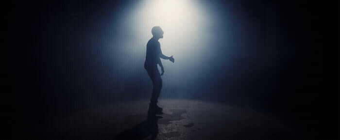 a man standing in a dark room with a light shining on him