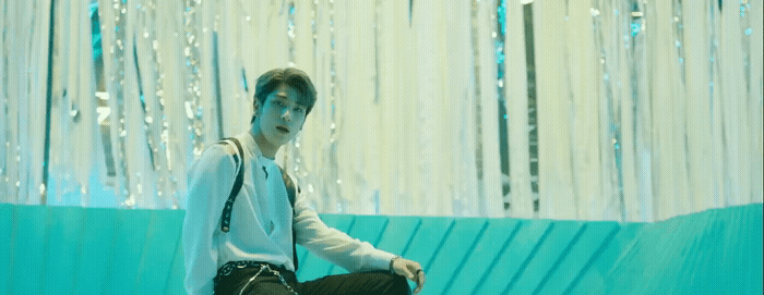 a man sitting on a stool in front of a blue wall