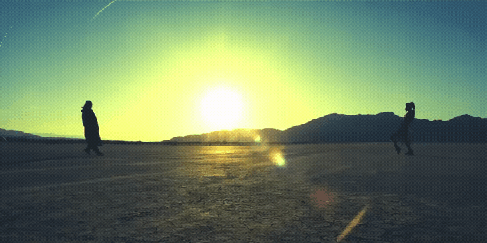 a couple of people walking across a desert