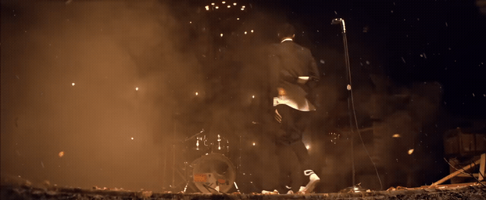 a man standing next to a drum set on a stage