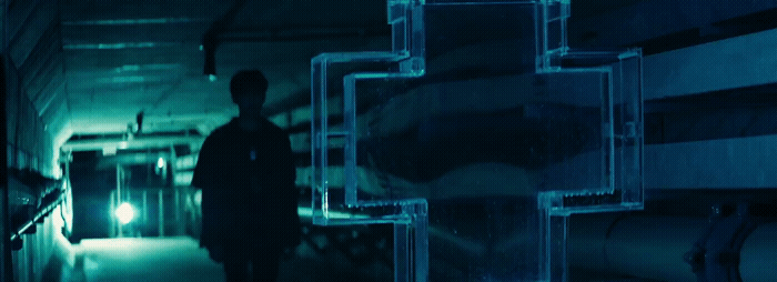 a man standing in a dark room next to pipes