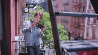 a woman standing on a balcony looking at her cell phone