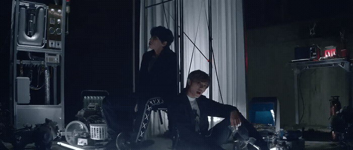 a man in a suit sitting on a chair next to another man in a suit