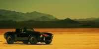 a black sports car driving across a desert plain