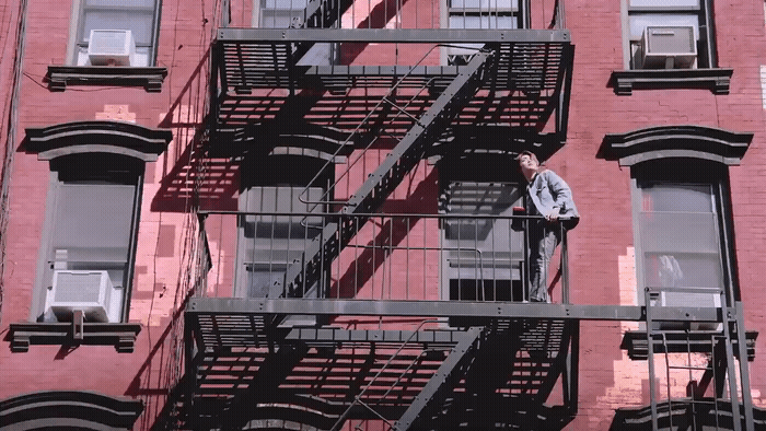 a man standing on a fire escape in front of a building