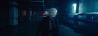 a man with white hair walking down a dark hallway