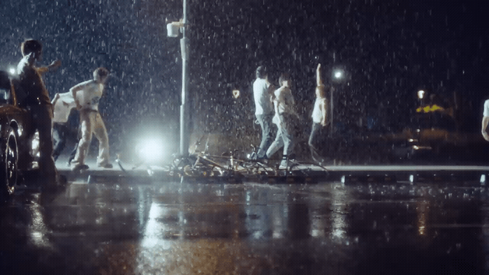 a group of people walking across a street in the rain