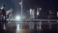 a group of people walking across a street in the rain
