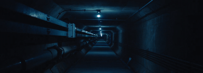 a long dark hallway with benches and lights