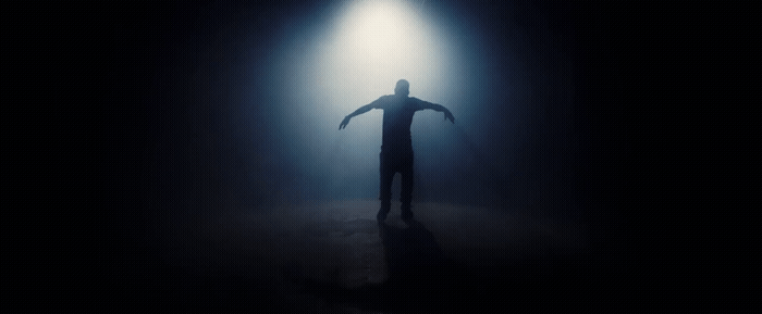 a man standing in the dark with his arms outstretched