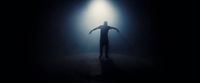 a man standing in the dark with his arms outstretched