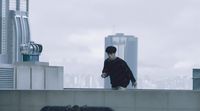 a man standing on top of a roof next to a tall building