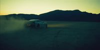 a car driving on a dirt road in the middle of the desert