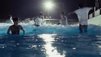 a group of people standing in a pool at night