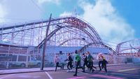 a group of people standing in front of a roller coaster